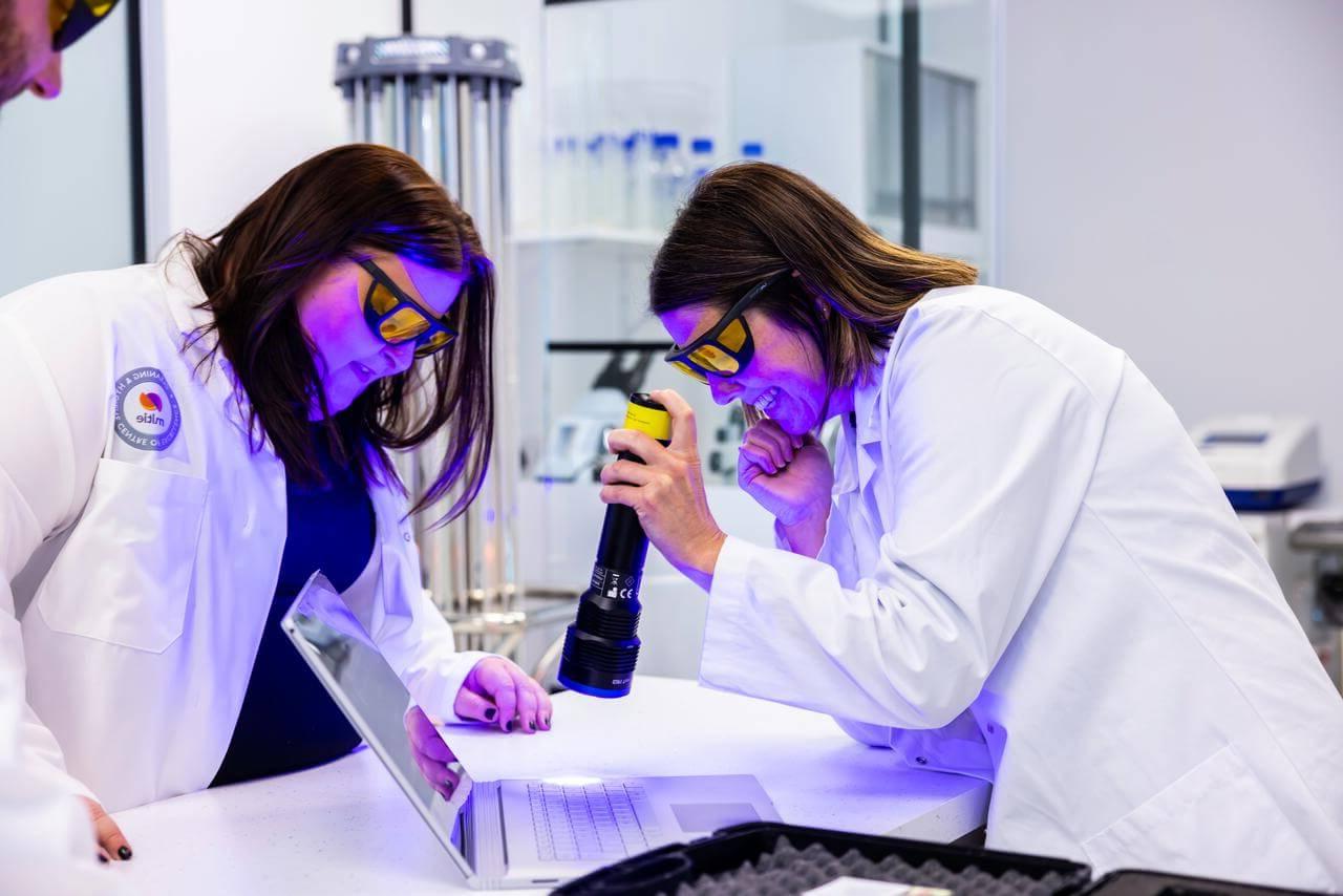 Mitie cleaning colleagues using a UV light on a laptop keyboard